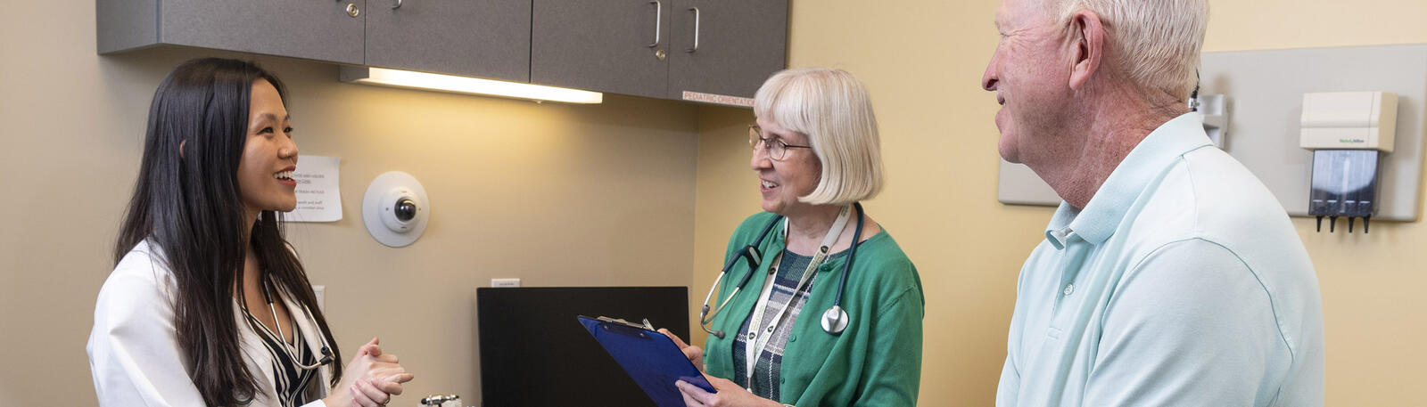 photo of a medical student, faculty member, and patient in an exam room